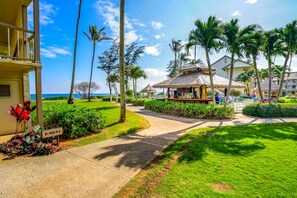 Un resort con un camino que lleva a una estructura de techo de paja, rodeado de palmeras y un césped bien cuidado.