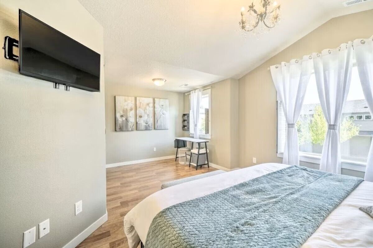 A bedroom with a bed, a desk, and a TV mounted on the wall.