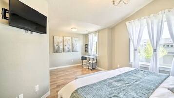 A bedroom with a bed, a desk, and a TV mounted on the wall.