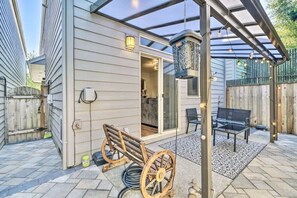 A covered patio area with a wooden bench, a table, and a hanging light fixture.