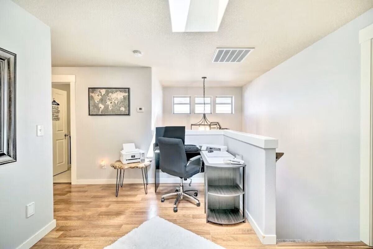A modern office space with a desk, chair, and shelving unit.