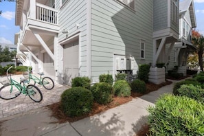 A two-story residential building with a front porch, a garage, and a bicycle parked outside. - Luxury Prominence Retreat | Bikes, Resort Pool & Walk to The Big Chill (Watersound)