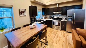 Une cuisine moderne équipée d’une table à manger, de chaises, d’un réfrigérateur et d’une cuisinière.