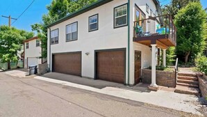 Une maison à deux étages avec un balcon, deux portes de garage et un petit porche à l’avant.