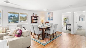 A modern living room with a dining area, a bookshelf, and a view of the outdoors.