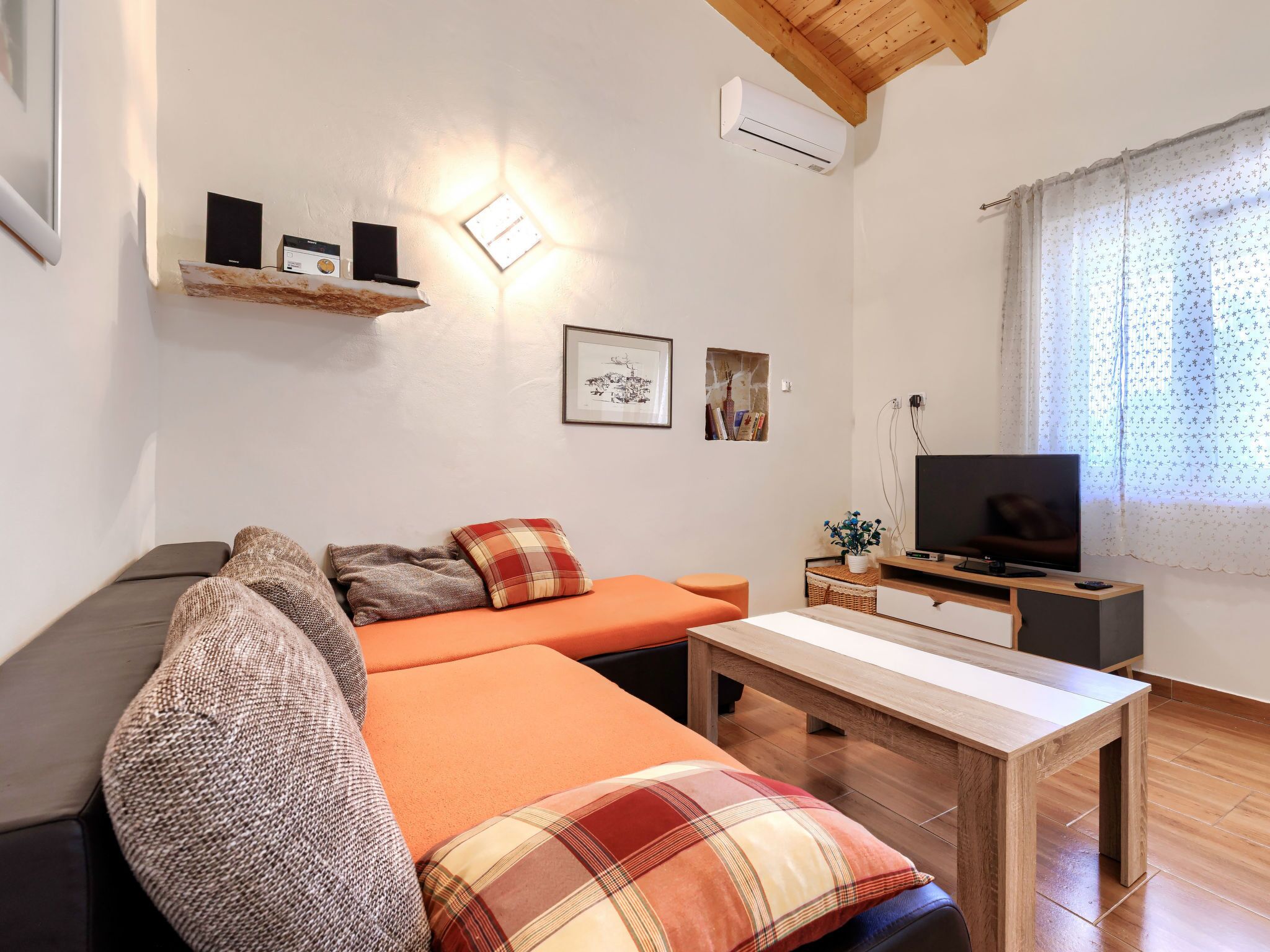 Ein modernes Wohnzimmer mit einer Couch, einem Couchtisch, einem Fernseher und einer Wandregal.
