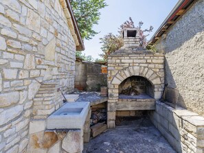 A stone-built outdoor kitchen area with a built-in oven, a sink, and a fire pit. - Erminia by Interhome (Svetvinčenat)