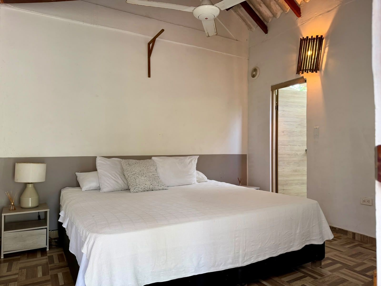 A bedroom with a bed, nightstand, lamp, and a ceiling fan.