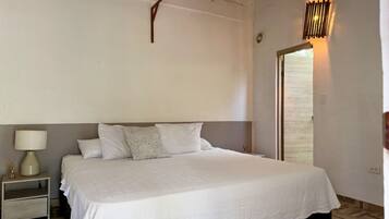 A bedroom with a bed, nightstand, lamp, and a ceiling fan.