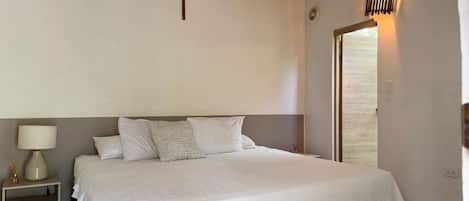 A bedroom with a bed, nightstand, lamp, and a ceiling fan.