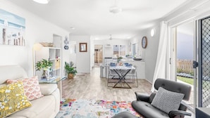 A modern living room with a sofa, a coffee table, and a dining area with a table and chairs. - Unit 1 (Anna) Beachside Mackay (Slade Point, Mackay)