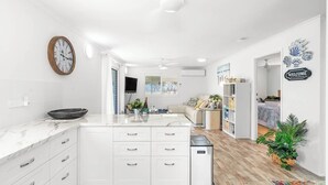 A modern kitchen with white cabinetry, a marble countertop, and a built-in island. - Unit 1 (Anna) Beachside Mackay (Slade Point, Mackay)