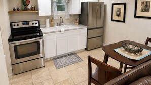 Eine kompakte Küche mit Herd, Backofen, Kühlschrank und einem Essbereich mit Tisch und Stühlen.