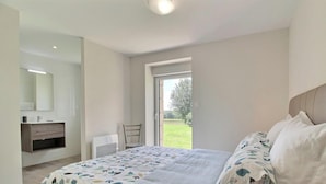 Ein Schlafzimmer mit Bett, Nachttisch, Stuhl, Fenster und Blick ins Freie.