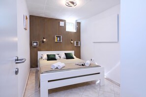 Een moderne slaapkamer met een bed, nachtkastjes, een wand van houten latten en een plafondlamp.