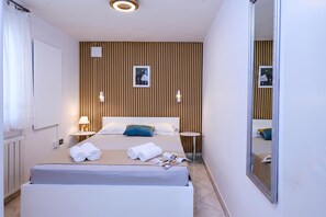 Ein modernes Hotelzimmer mit einem großen Bett, Nachttischen, einem Spiegel und einer Wandpaneele aus Holz.