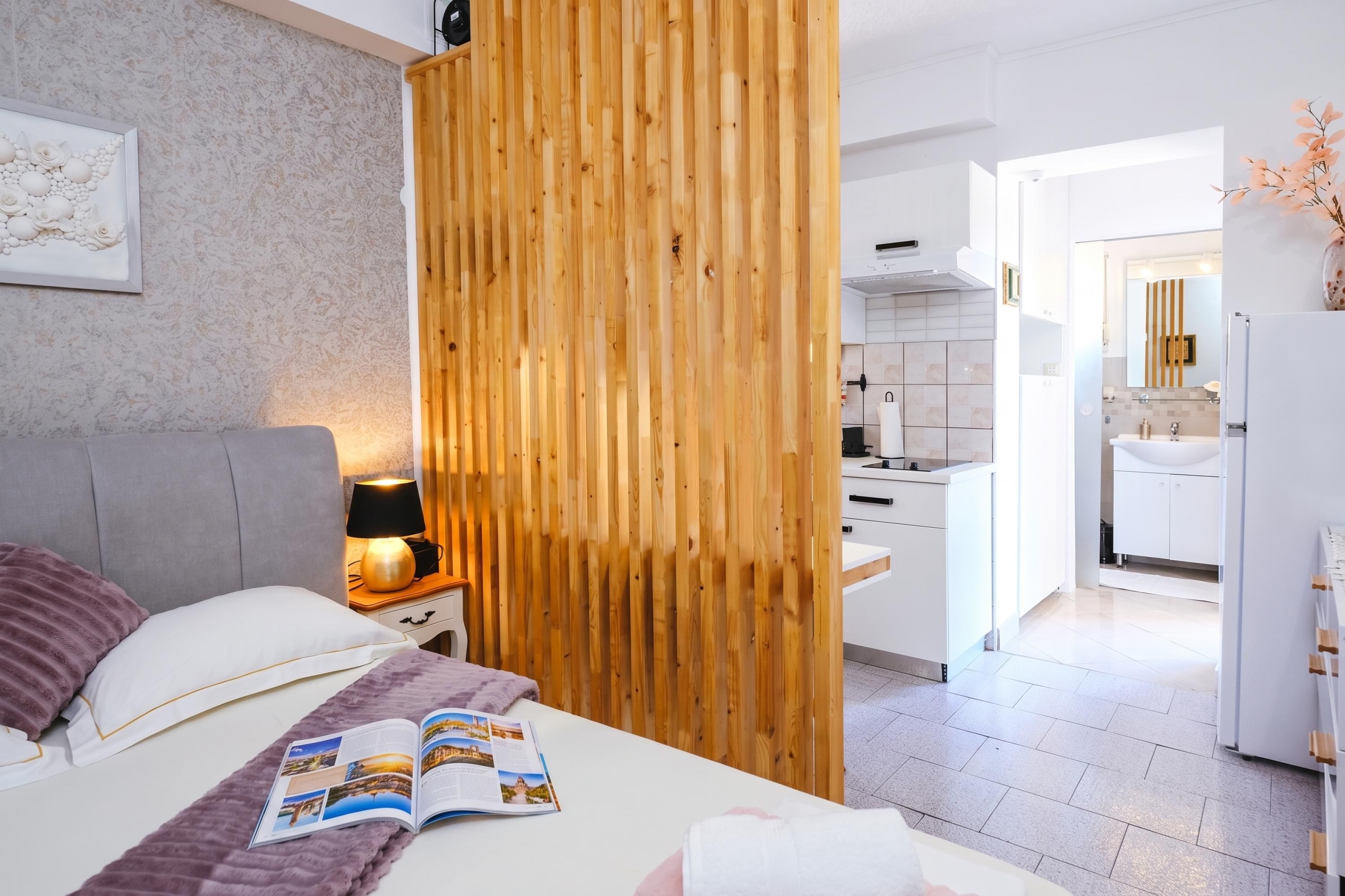Habitació d'hotel moderna amb llit, taulell de nit, làmpada i una revista.