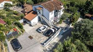 Un edificio a due piani con tetto in tegole, un'area parcheggio coperta e una scala che conduce al piano superiore.