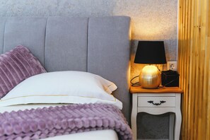 A neatly made bed with a purple blanket and pillows, a bedside lamp, and a small wooden nightstand with a drawer. - Studio Nik Garden & Jacuzzi near Portoroz, Portorož - Sečovlje, Slovenia (Portorož - Sečovlje)