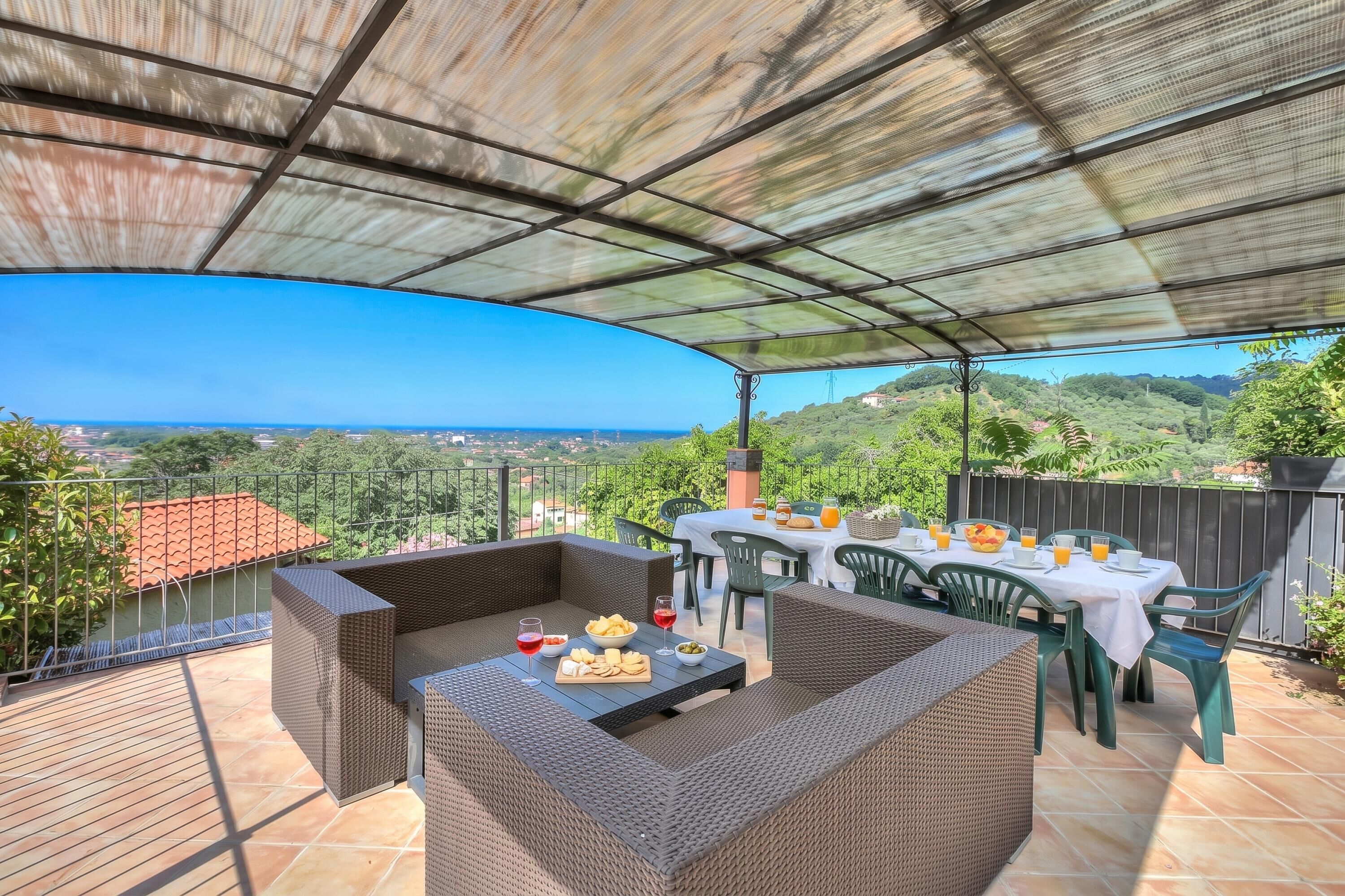 Un patio esterno con una zona salotto riparata, un tavolo da pranzo per due e una vista panoramica sul paesaggio.