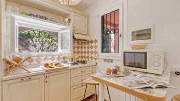 Una cucina con finestra, un forno a microonde, un fornello e un piccolo angolo ristoro con tavolo e sedie.