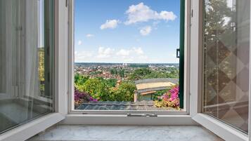Una finestra con vista sullo skyline cittadino, un balcone e un cielo sereno.