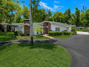 A two-story house with a brick exterior, a front porch, and a driveway leading to a garage. - 5BR Estate: Heated Pool, Hot Tub & Movie Theater (Seminole)