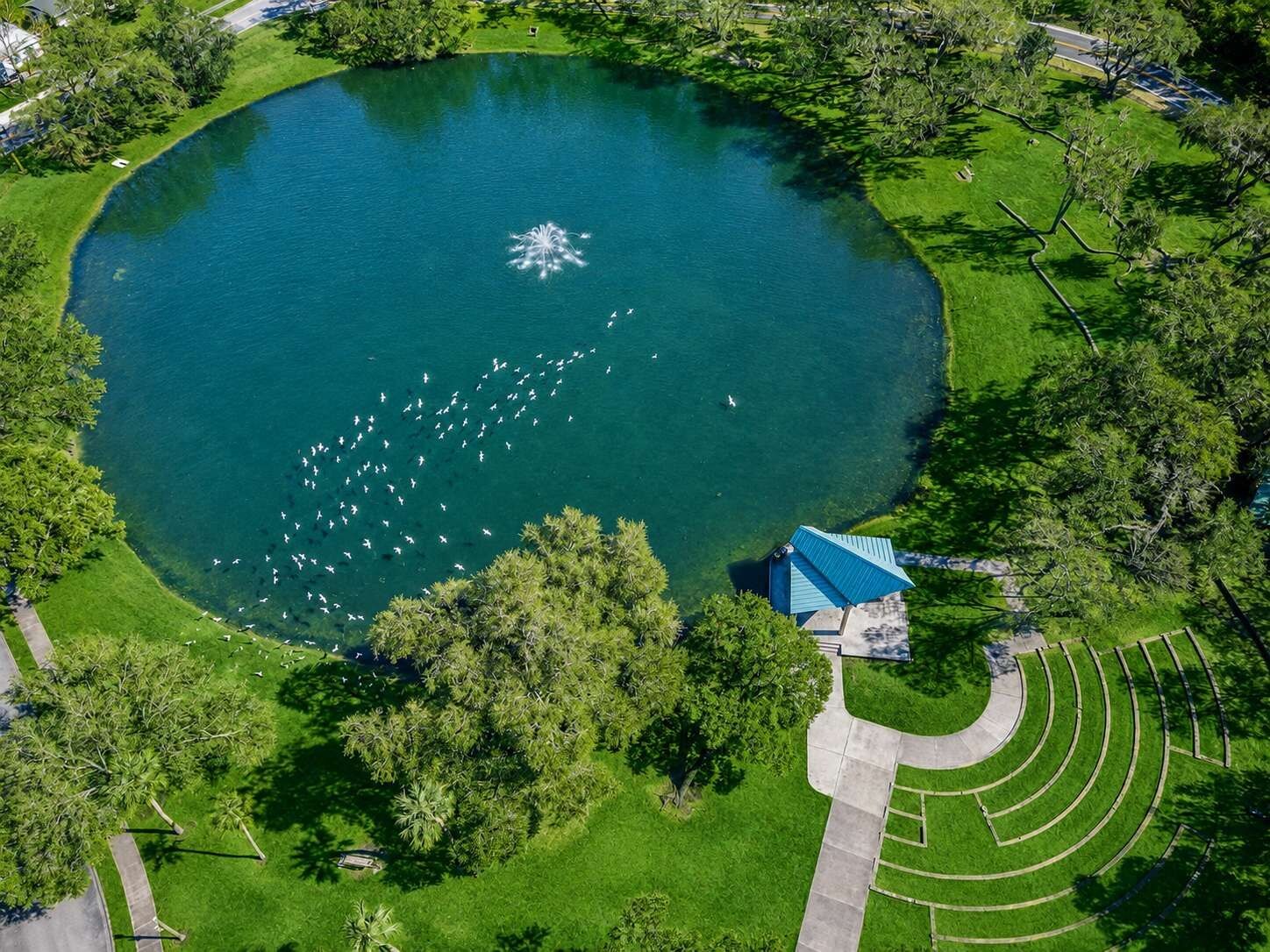 Vista aérea de un parque con un gran estanque, una fuente y un pabellón.