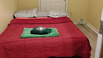 Un lit avec une couvre-lit rouge, un oreiller vert et un oreiller blanc.