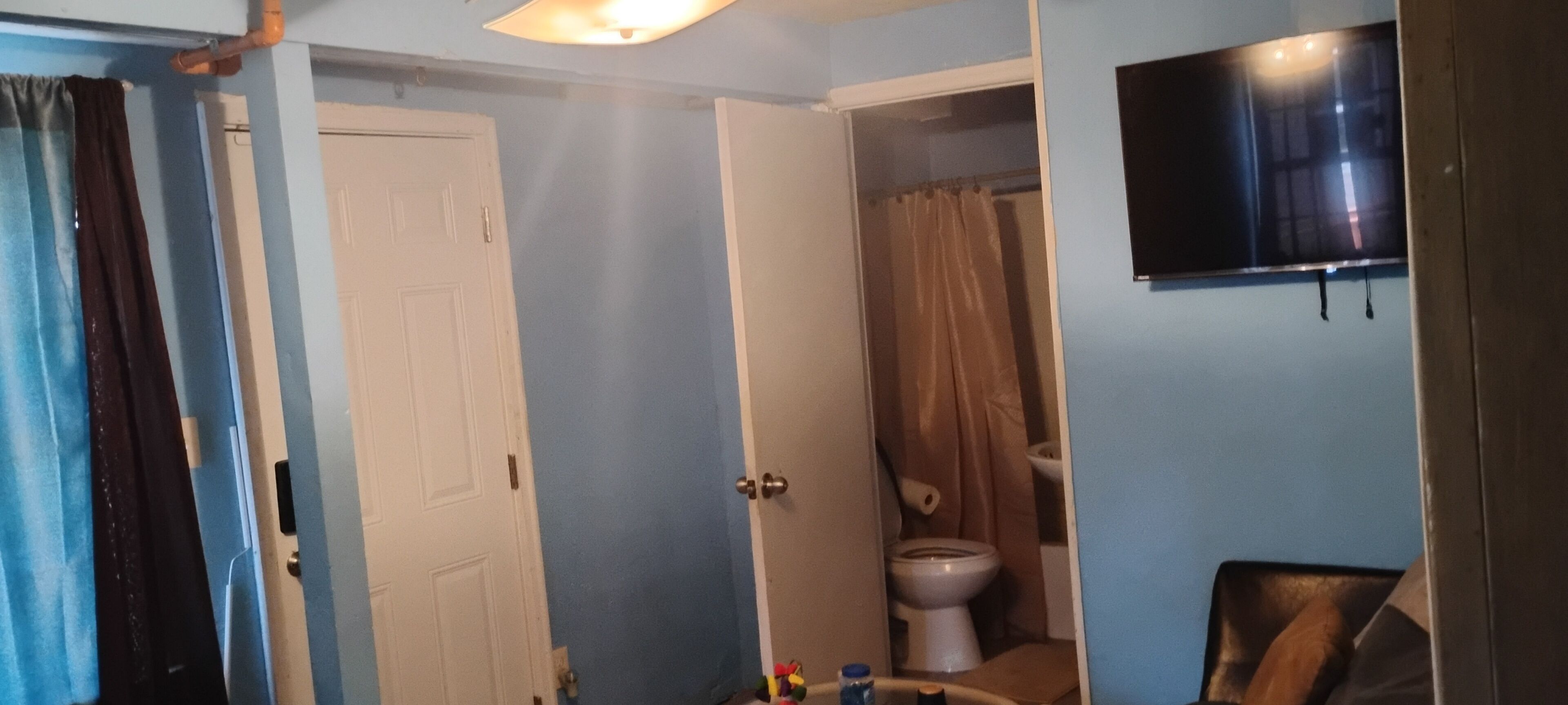 Une salle de bain équipée de toilettes, d’un rideau de douche et d’un téléviseur fixé au mur.