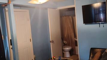 Une salle de bain équipée de toilettes, d’un rideau de douche et d’un téléviseur fixé au mur.