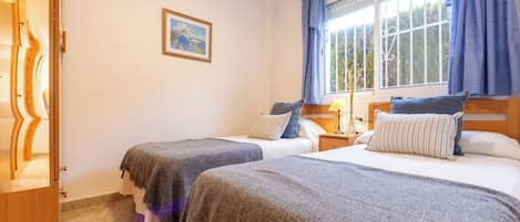 Un dormitorio con dos camas, un armario de madera, una ventana con cortinas y un cuadro en la pared.