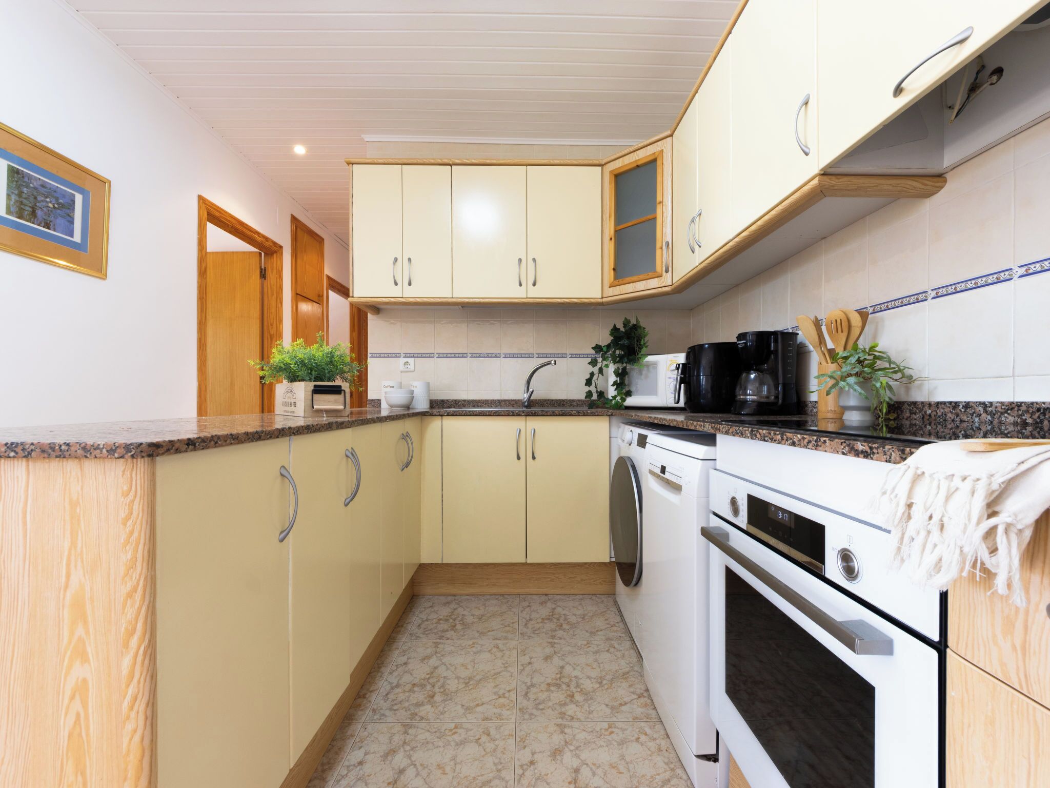 A compact kitchen with a washing machine, a coffee maker, and a microwave.