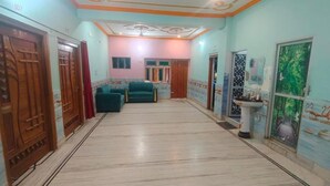 A hallway with a marble floor, wooden doors, a teal sofa, and a wall with a mural.