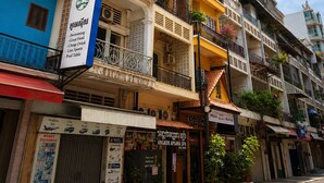 A multi-story building with balconies, a sign for 'Dynasty,' and a 'Cambodia' sign with amenities listed. - Dynasty Boutique Hotel (Phnom Penh)