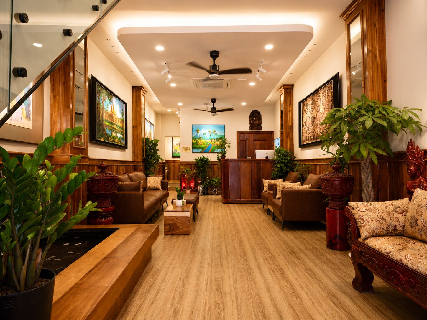 A spacious living area with leather sofas, wooden flooring, and large paintings on the walls.