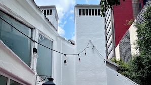 Un edificio con fachada blanca, un farol negro y una guirnalda de luces.