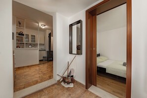 Un dormitorio con cama, una puerta de madera, un espejo y una pequeña decoración náutica en el suelo.