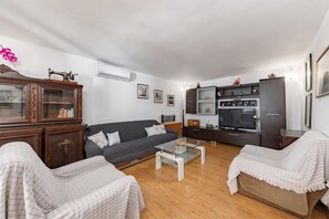 Un salon comprenant un canapé, une table basse, un meuble et un téléviseur.