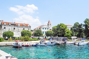 Ein Yachthafen mit vertäuten Booten, eine Kirche mit Glockenturm und Gebäude mit Balkonen.