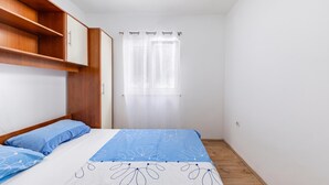 Ein Schlafzimmer mit einem Bett, einem Kleiderschrank, einem Fenster mit Vorhängen und einem Deckenventilator.