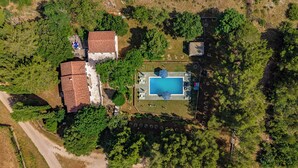 Luftaufnahme eines Grundstücks mit Swimmingpool, umzäunter Garten und einem Gebäude mit rotem Dach.
