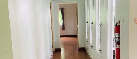 Un couloir doté d’un plancher en bois, de murs blancs et d’un extincteur fixé au mur.