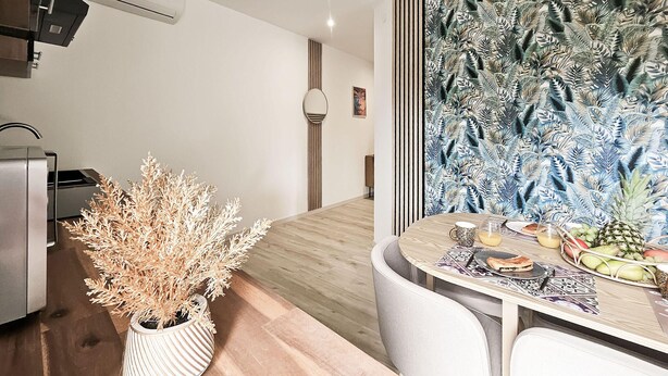 A modern kitchen with a wooden countertop, a potted plant, and a dining area with a table set for two. - Cozy apartment in Cierzac with WiFi (Cierzac)