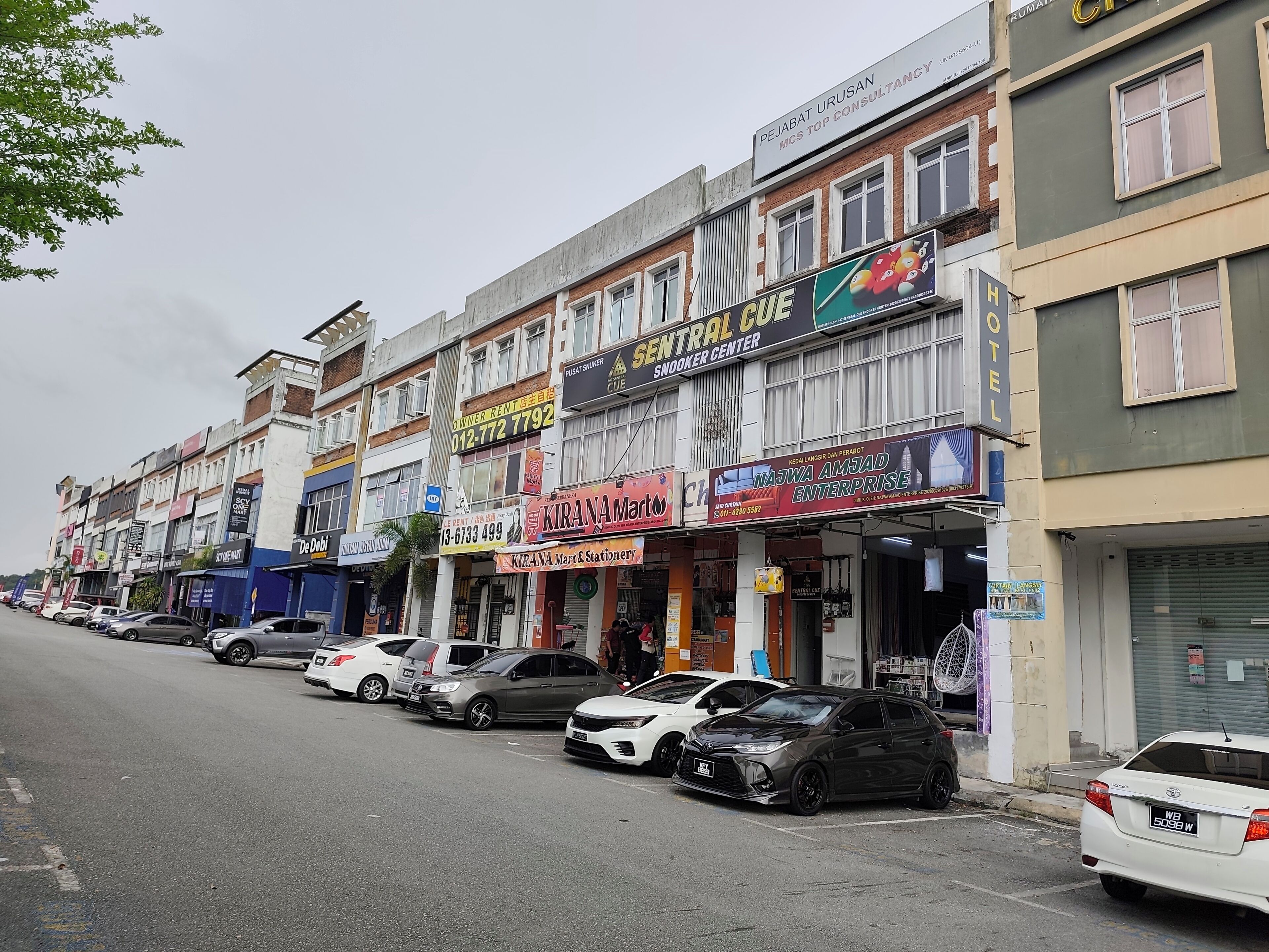 Uma fileira de edifícios comerciais com diferentes fachadas, incluindo um hotel e um centro de sinuca.