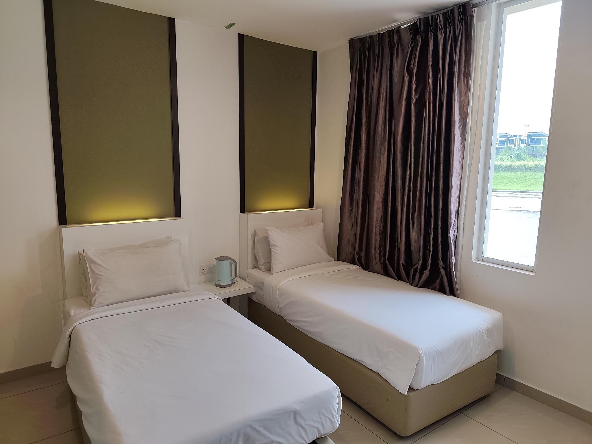 Een hotelkamer met twee enkele bedden, een klein tafeltje met een waterkoker en een raam met gordijnen.