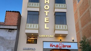 Un hotel con un letrero grande que dice 'HOTEL', un letrero de 'LIBERTAD' debajo y un escaparate de 'Krull Bros'.