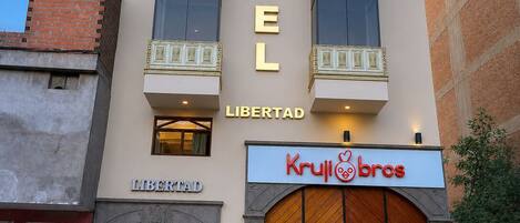 A hotel with a prominent 'HOTEL' sign, a 'LIBERTAD' sign below, and a 'Krull Bros' storefront.