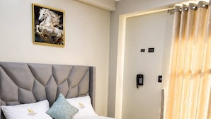 Una habitación de hotel con cama, un cuadro, un teléfono y una cortina.