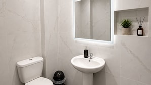 Un baño moderno con inodoro, lavamanos y espejo.